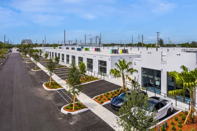 White commercial buildings beside landscaped parking at Thrive Art District, Fort Lauderdale